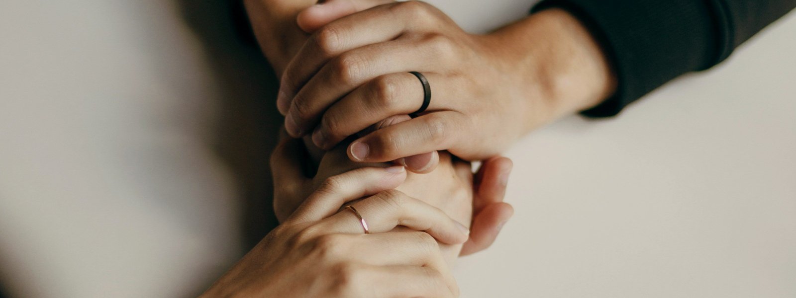 Duas pessoas de mãos dadas sobre uma mesa, em tom escuro e sóbrio, em um gesto de acolhimento. Texto: "Dia Mundial da Saúde Mental. Ser ouvido também é cuidado." Dr. Guilherme Loureiro Fracasso, Médico Psiquiatra, CRM-RS 36.500 | RQE 32.771.
